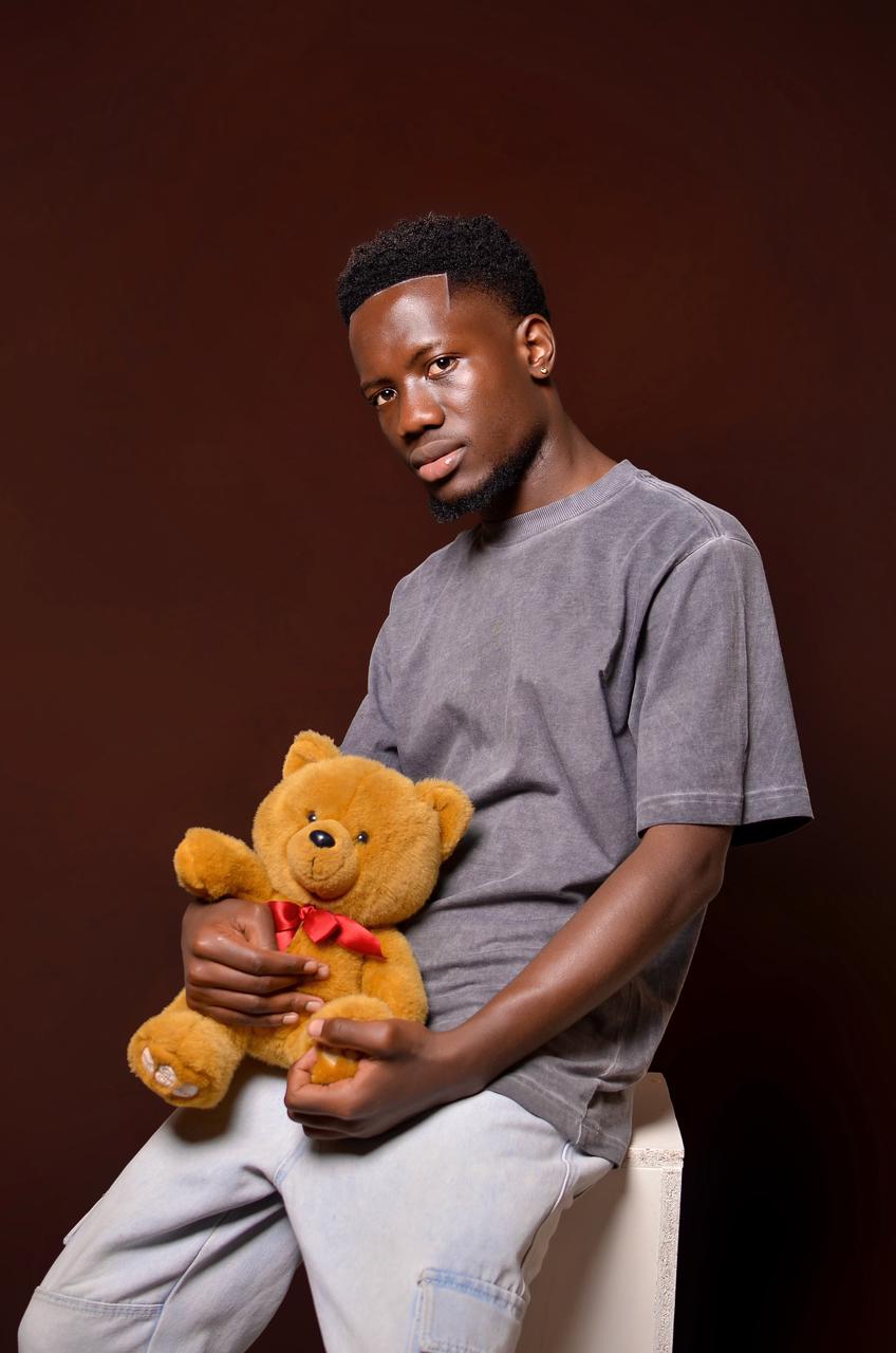 Man holding a teddy bear against a dark background